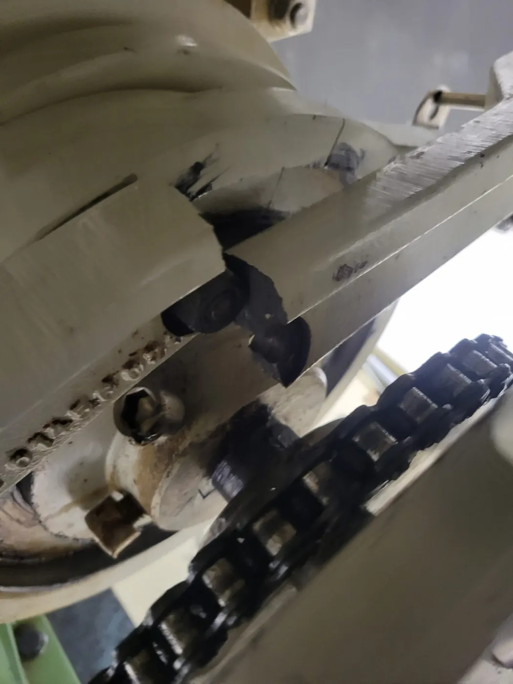 Cam arm and cam follower being replaced on a capsule filling machine, with the cam track and roller drive chain exposed.